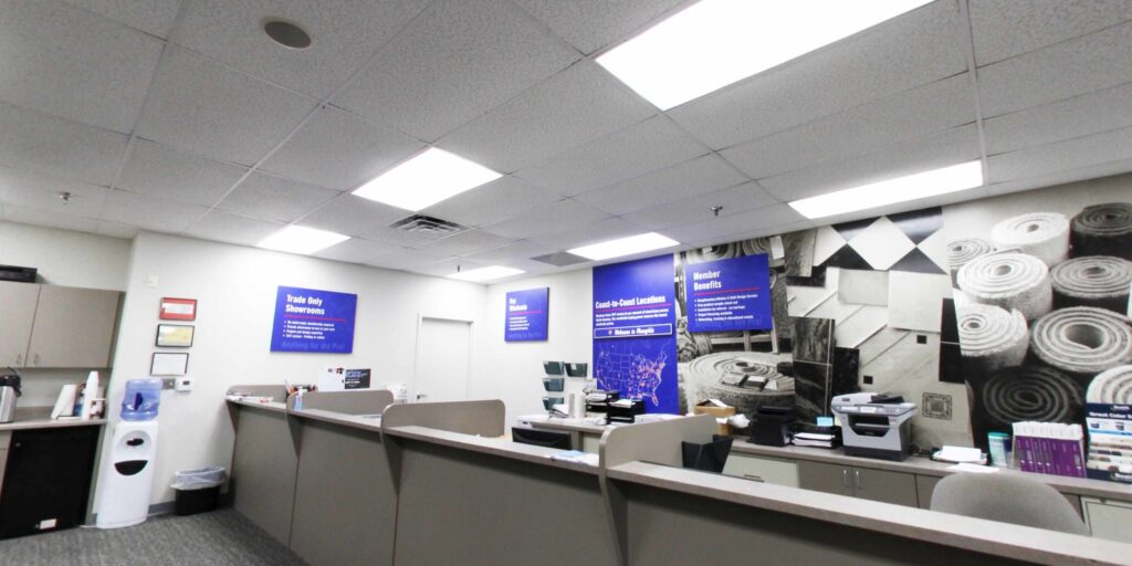 Reception area of ProSource Memphis showroom with carpeted floor and wall graphic of rolled carpets in Bartlett, TN.