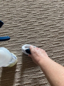 A hand using a specialized tool for spot cleaning on a textured carpet by Heaven's Best Carpet Cleaning in Oklahoma City, OK.
