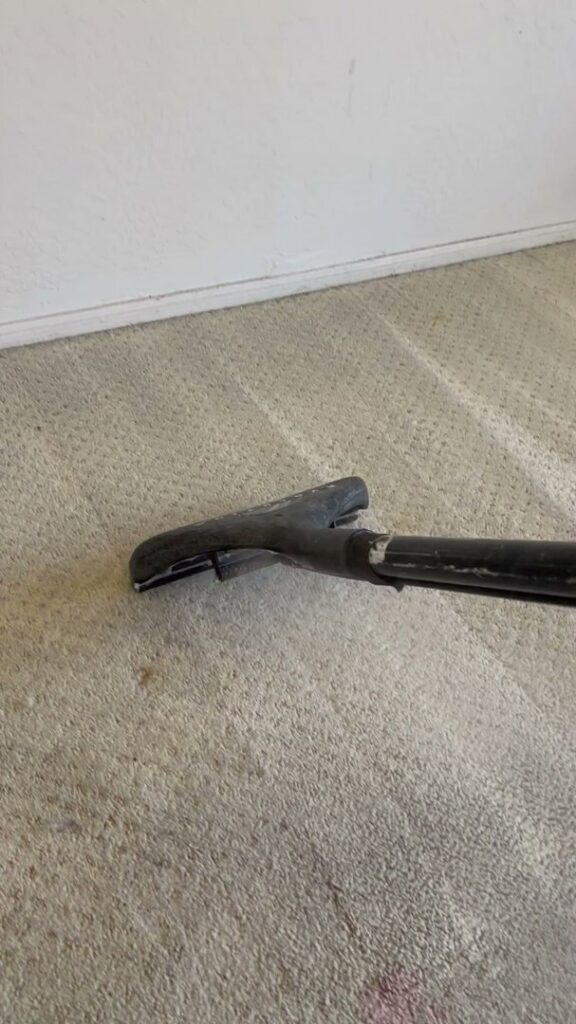 A carpet cleaning wand removing a red stain from a light-colored carpet by Specialty Carpet Care in Surprise, AZ