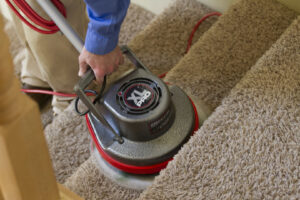 A professional cleaning carpeted stairs with a specialized machine from Heaven's Best Carpet Cleaning in Oklahoma City, OK.