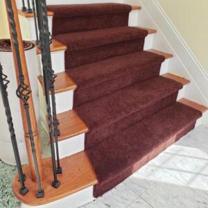 A newly installed dark red carpet stair runner on a wooden staircase by FloorCrafters in Toms River, NJ
