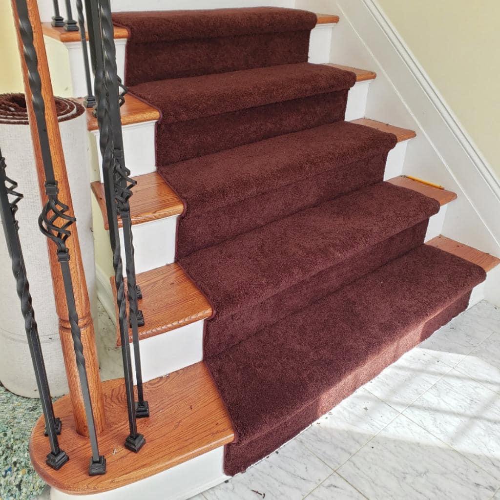 A newly installed dark red carpet stair runner on a wooden staircase by FloorCrafters in Toms River, NJ