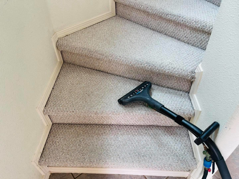 A professional cleaning carpeted stairs with a specialized wand by DEEP CLEAN Carpet Cleaners in Beaverton, OR