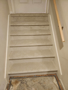 Carpeted stairs showing subfloor and tack strips, indicating a carpet installation by Zubeck Flooring in Blue Springs, MO