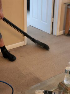 Close-up of a professional performing carpet steam cleaning with a wand at Healthy Homes Cleaning and Restoration LLC in Fort Lauderdale, FL.