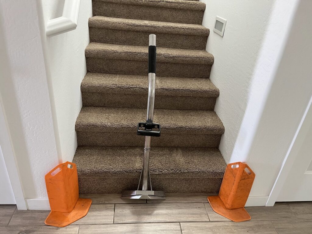 A carpet stretcher tool on carpeted stairs, showing carpet installation or repair by Fusioncarpetcleaning in Fort Walton Beach, FL