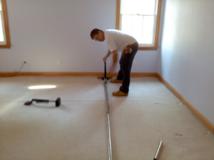 A carpet repair specialist performing a carpet stretching and installation job for Carpet Repair Specialists in Litchfield, NH.