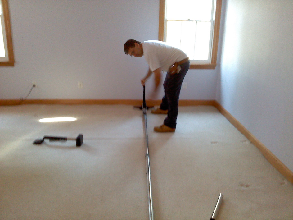 A carpet repair specialist performing a carpet stretching and installation job for Carpet Repair Specialists in Litchfield, NH.