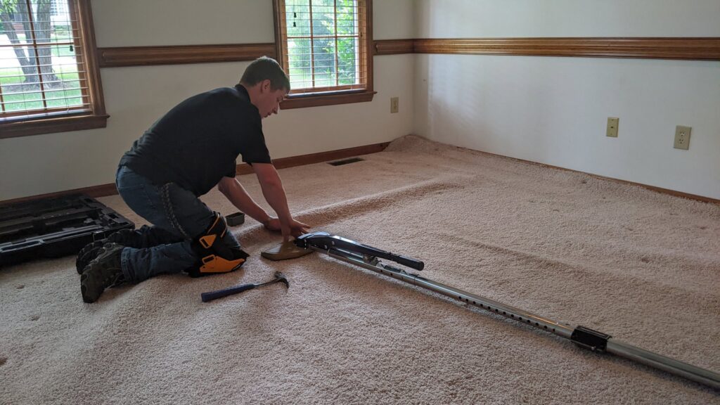 A technician stretching carpet with a power stretcher for Regional Carpet Care in Garner, NC.