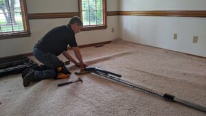 A technician stretching carpet with a power stretcher for Regional Carpet Care in Garner, NC.
