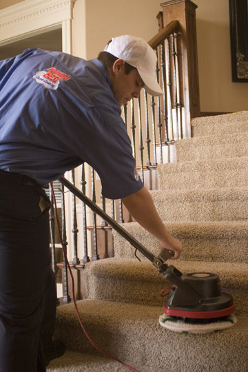 A Heaven's Best Carpet Cleaning technician cleaning carpeted stairs with a rotary machine in Idaho Falls, ID.