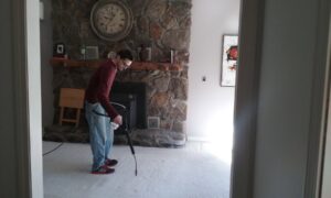 A carpet technician inspecting and treating a carpet with a handheld tool for Glory Carpet Cleaning Service in East Hartford, CT.