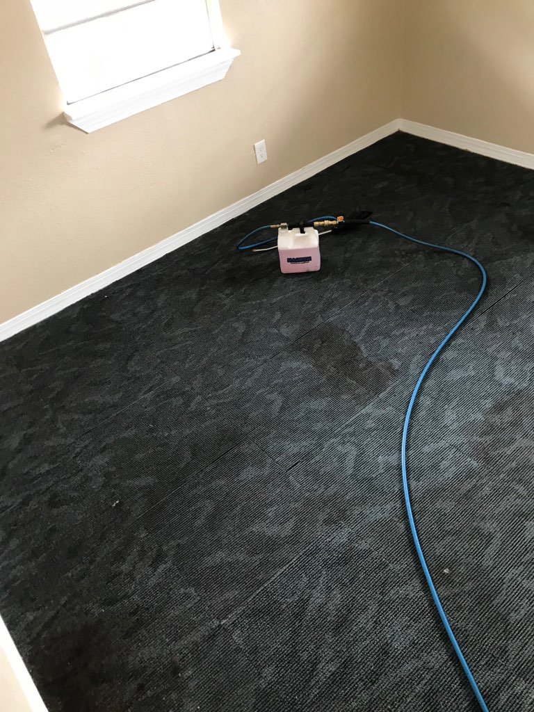 Equipment and hoses on dark grey carpet tiles, indicating a cleaning job by Tex A Clean Carpet Care in League City, TX.