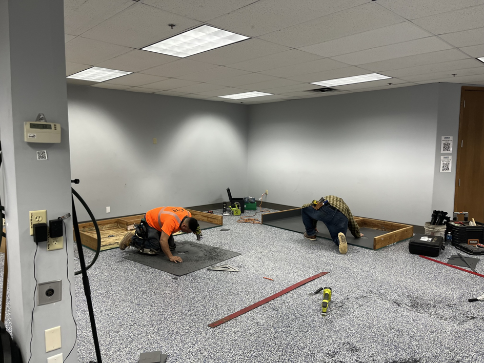 Two skilled workers kneeling and actively installing carpet tiles for a client by Hank's Specialties, Inc. in Saint Paul, MN.