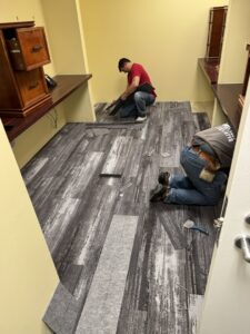 Carpet contractors installing new carpet tiles in an office space for Harry's Carpet One in Quincy, MA.