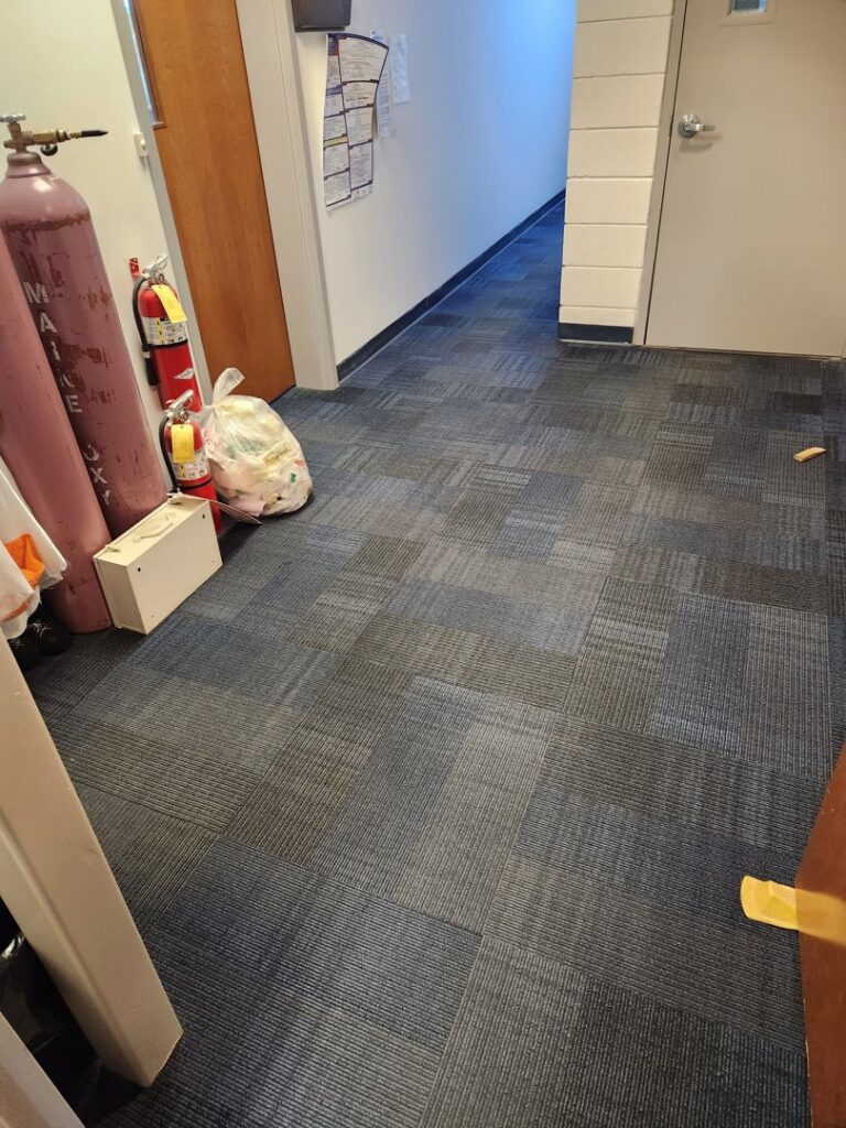 Carpet tiles being installed near a window in a commercial setting, showcasing work by Carpet Center in Nashua, NH.