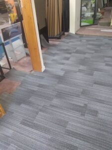 Carpet tile installation work in progress, showing rolled-up tiles, by Carpet Center in Wilmington, NC.