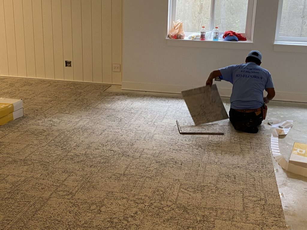 A worker installing carpet tiles during a flooring project by C&H Installation Group LLC in Schaumburg, IL