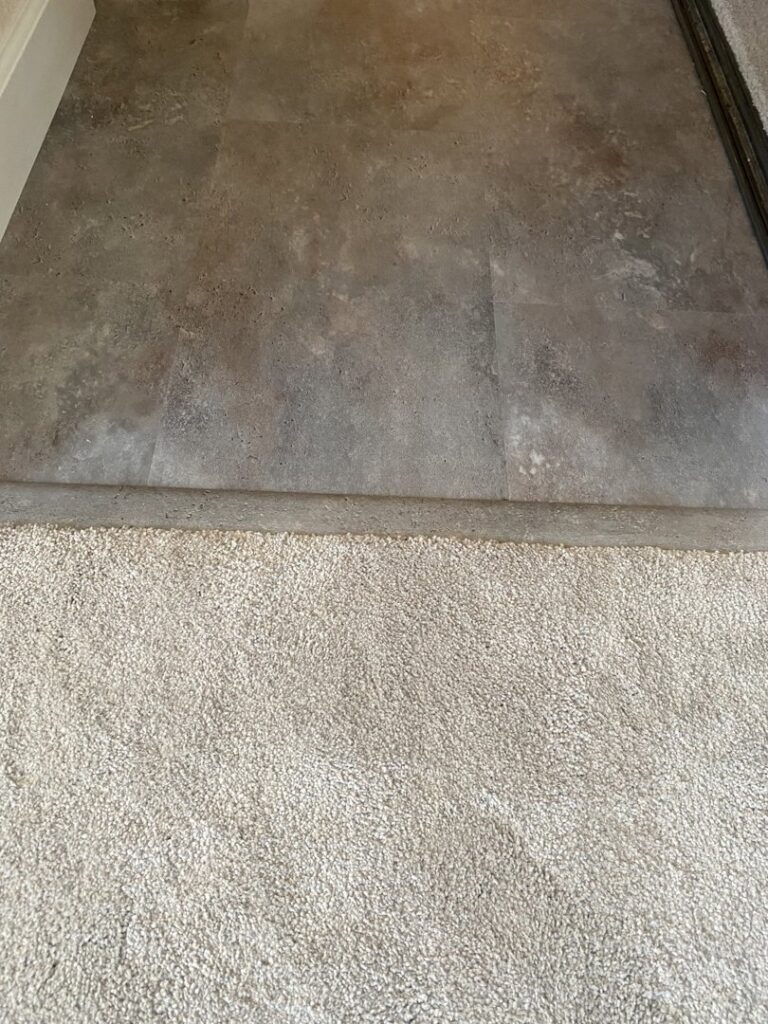 A close-up view of a clean transition between carpet and tile flooring by Floor & More in San Marcos, CA.