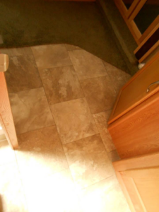 A seamless transition from green carpet to light brown tile-patterned vinyl flooring installed by Frosty's Carpet Center, Inc. in Grand Forks, ND.