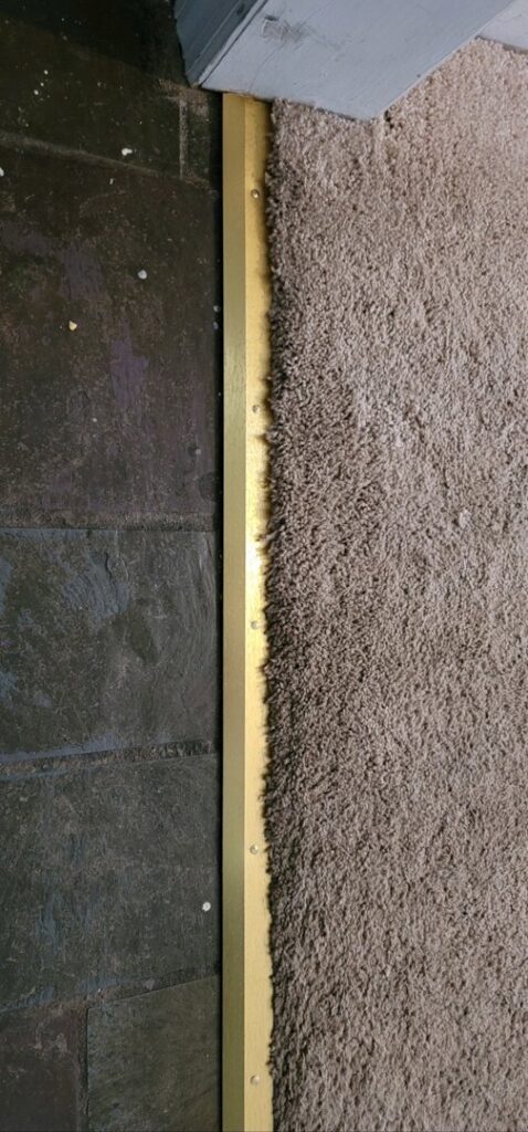 Close-up of a carpet to tile transition strip installation by American Flooring Specialists in Albany, NY.