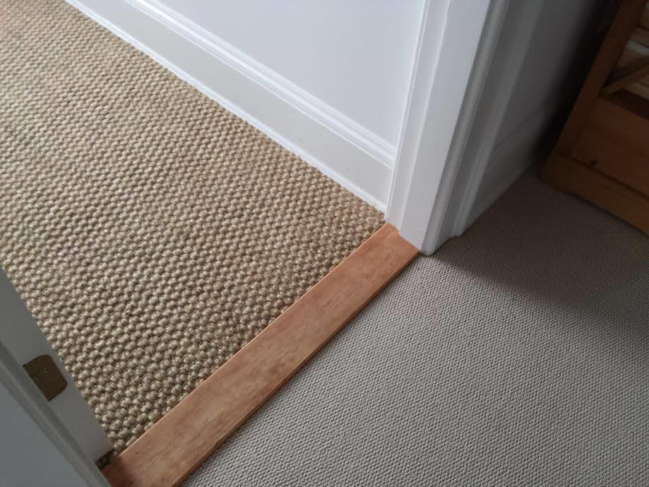 A professional carpet transition installation with a wooden strip in a doorway by Karpet Klinic Inc. in Cranston, RI