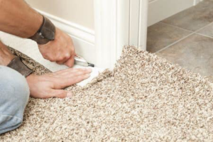 A carpet contractor trimming new carpet during installation at a home by Minot Flooring in Minot, ND.