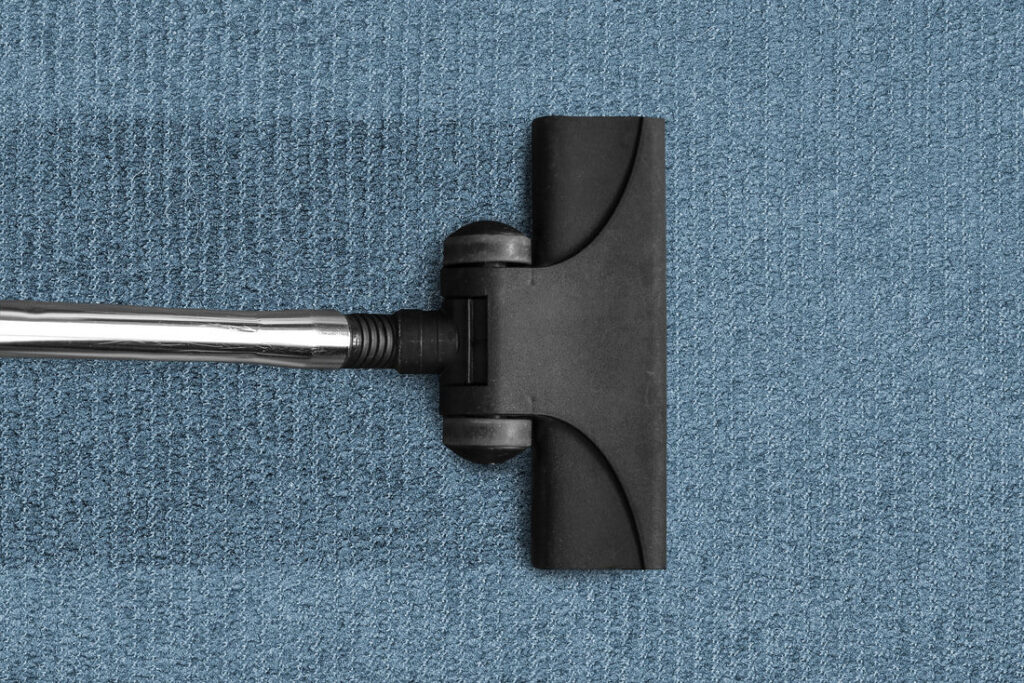 A vacuum cleaner head showing a clean line on a blue carpet, demonstrating cleaning services by stpaulbestcarpetcleaners.com in Saint Paul, MN.