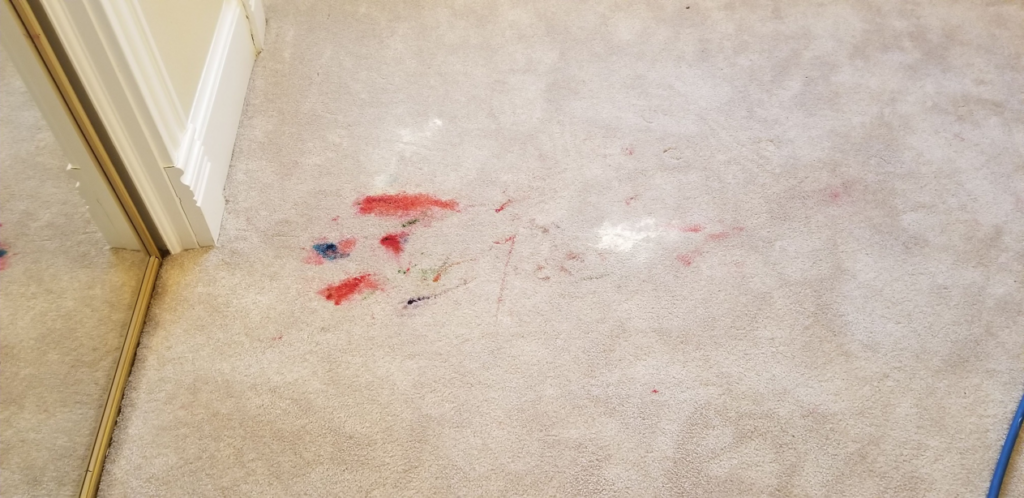 A light-colored carpet with colorful stains before professional cleaning by The Carpet Medic in Suffolk, VA