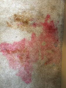 A light-colored carpet with a large red stain requiring professional removal by Sunshine Carpet Cleaning Services in Houston, TX