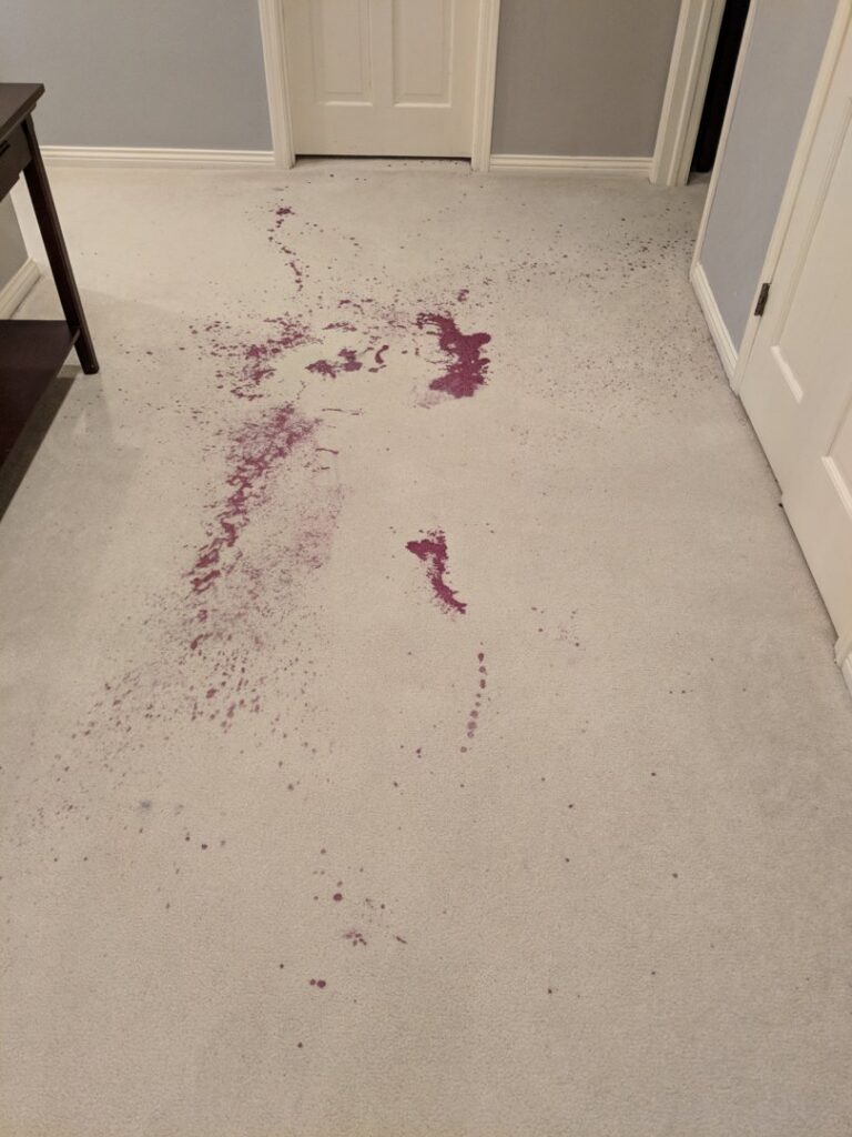 A light-colored carpet with a significant red wine stain, awaiting professional cleaning by Real Green Cleaning in Indianapolis, IN.