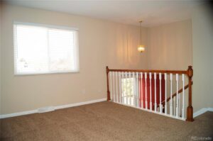 A bright, carpeted loft area with a large window, showcasing a completed project by Carpet Connection of Denver in Aurora, CO.
