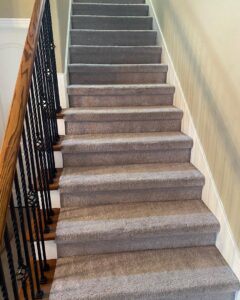 A clean, grey carpeted staircase, showcasing quality carpet work by The Floor Care Guys in Bentonville, AR.