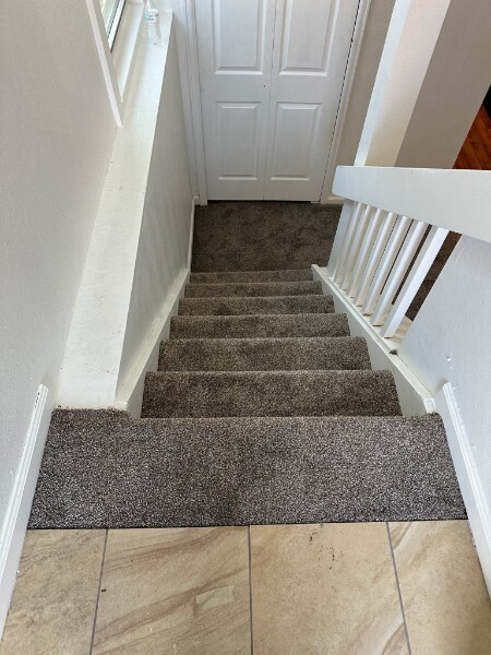 Newly installed carpet on a staircase leading to a tiled floor by Floors By Tomorrow in Aurora, CO