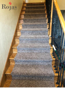 A carpeted staircase with dark gray speckled carpet, demonstrating a quality installation by Rojas Carpet and Flooring in Denver, CO.