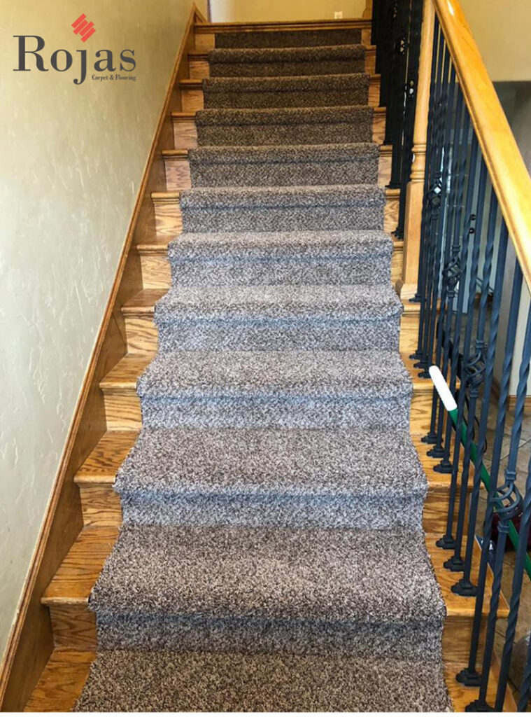 A carpeted staircase with dark gray speckled carpet, demonstrating a quality installation by Rojas Carpet and Flooring in Denver, CO.