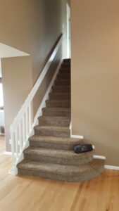 A carpeted staircase with white railing, showcasing a completed installation by Carpet Connection of Denver in Aurora, CO.