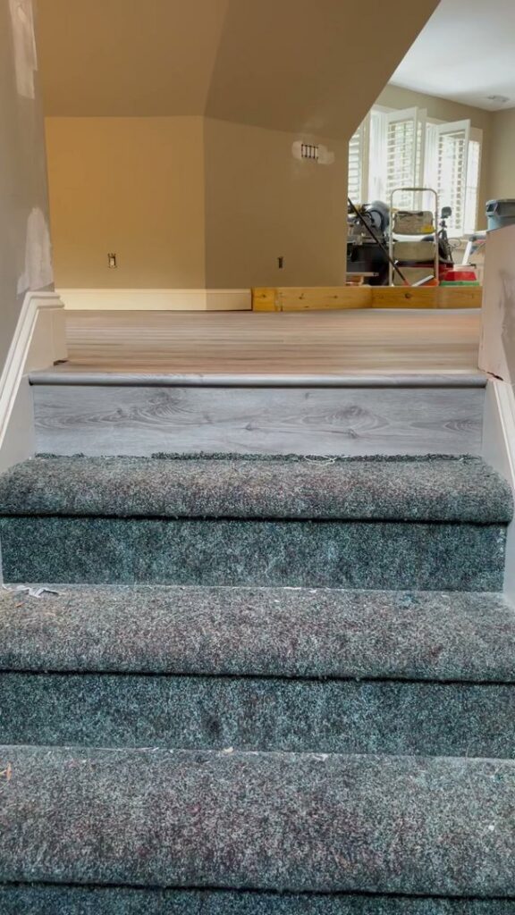 Carpeted stairs leading to a landing with new hard flooring by Atlas Flooring & Design in Raleigh, NC.