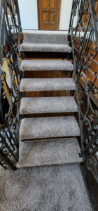 Newly installed gray carpet on a staircase with decorative wrought iron railings by B A Carpet and Flooring in Broken Arrow, OK.