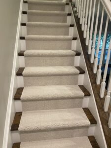 Newly installed light-colored carpet on stairs with dark wood risers by Ceramic City USA in Houston, TX