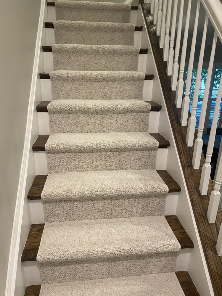 Newly installed light-colored carpet on stairs with dark wood risers by Ceramic City USA in Houston, TX