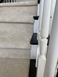 Newly installed light-colored carpet on stairs with white and black banister by Floor Gallery in Pearland, TX