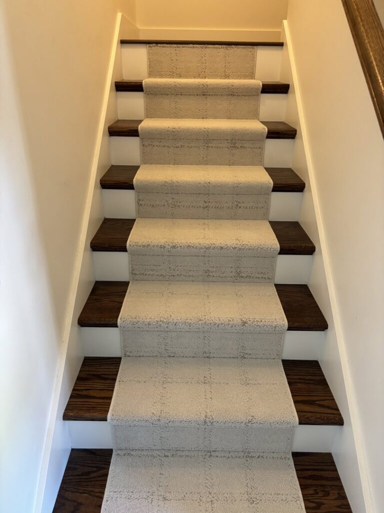 Newly installed light-colored carpet runner on dark wood stairs by Johnson City Flooring & Finish, LLC in Johnson City, TN