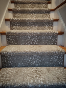 Close-up of a newly installed patterned carpet runner on wooden stairs by Persian Rug Gallery in Nashua, NH.