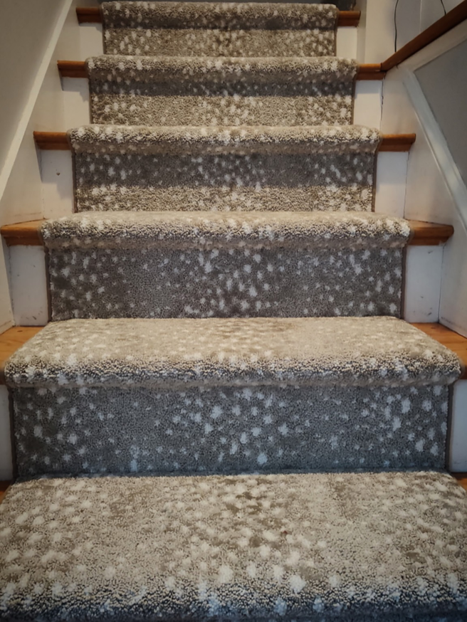 Close-up of a newly installed patterned carpet runner on wooden stairs by Persian Rug Gallery in Nashua, NH.