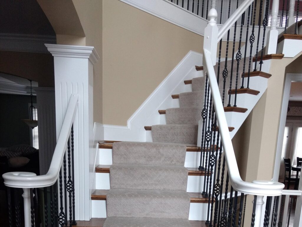 Elegant carpeted stairs with white banisters and dark metal spindles, installed by Home Based Carpet & Flooring in Cincinnati, OH.