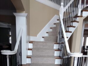 Elegant carpeted stairs with white banisters and dark metal spindles, installed by Home Based Carpet & Flooring in Cincinnati, OH.