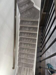 View of carpeted stairs with a modern railing, showcasing carpet installation or cleaning by Utah Carpet Systems in Orem, UT.