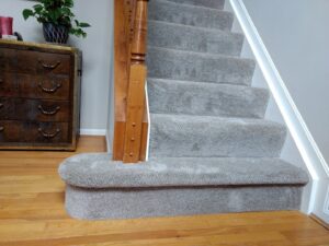 Beautifully carpeted stairs with a wooden banister, showcasing quality work by Home Based Carpet & Flooring in Cincinnati, OH.