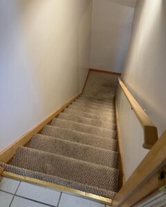 A carpeted stairwell leading to a tiled floor, expertly installed by Trent's Carpet Cleaning & Restoration in Fishers, IN.